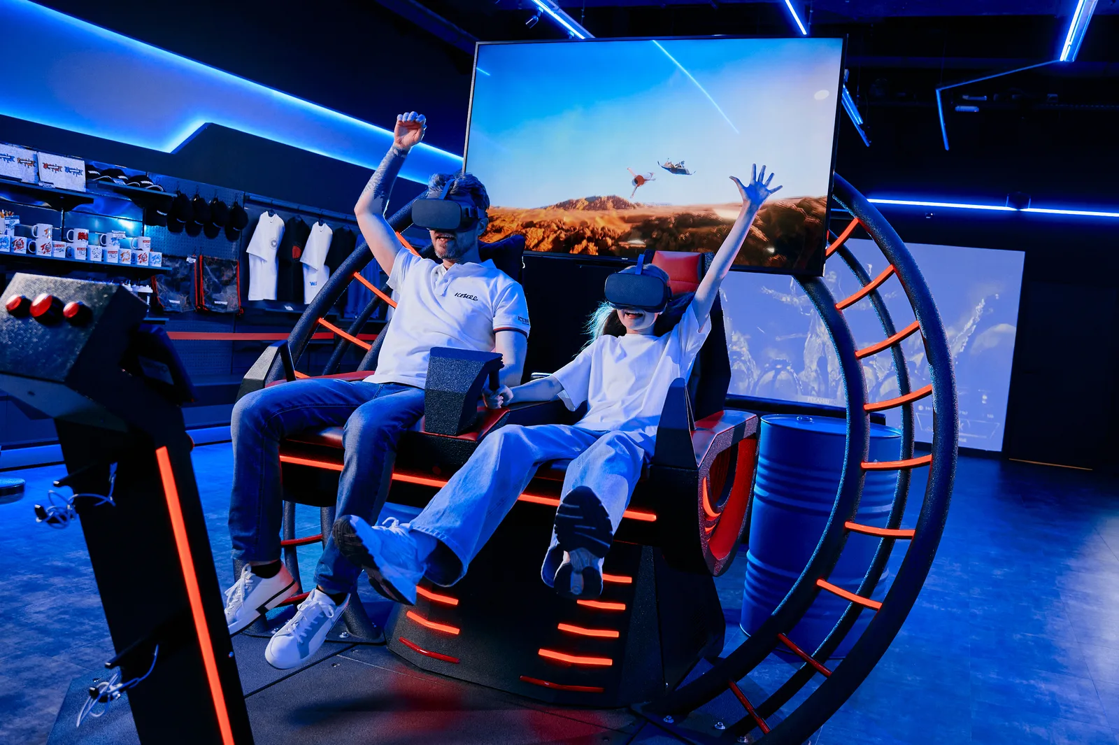 A father and daughter with raised hands on a ring-shaped VR attraction, a flight scene on the screen