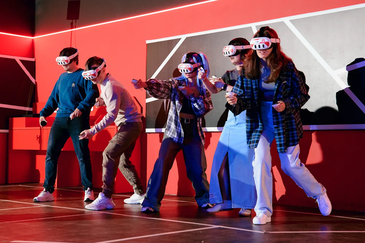 A group of friends in VR headsets on the red floor of the arena